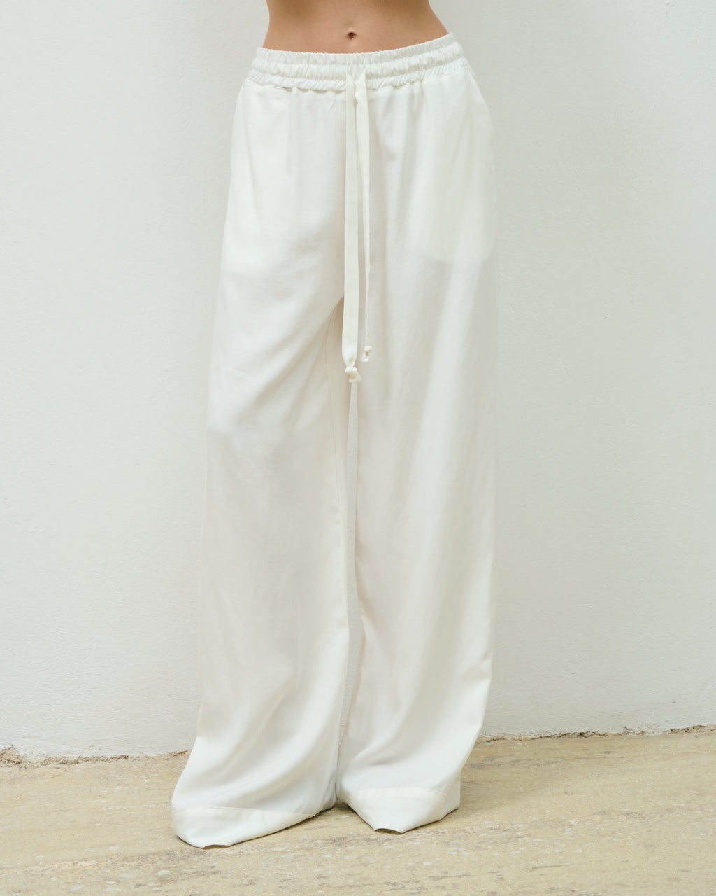 Close-up of the white Sunday Trousers, elasticated waistband and drawstring tie