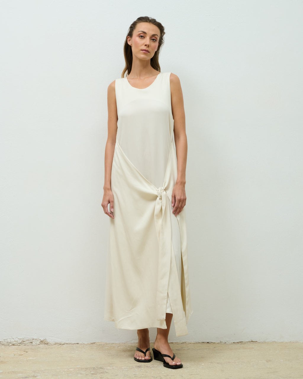 Model wearing the beige Elena Dress with the wrap-tie detail, full-length front view