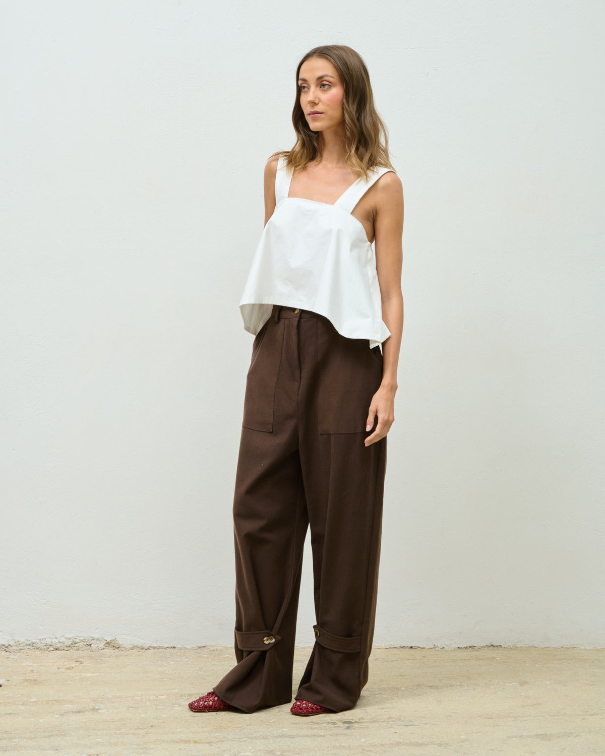 Model wearing the brown Poly Trousers with a white top, full-length front view