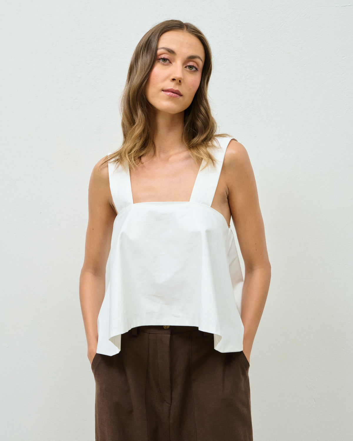 Model wearing the white Sunday Top with brown wide-leg trousers, front view